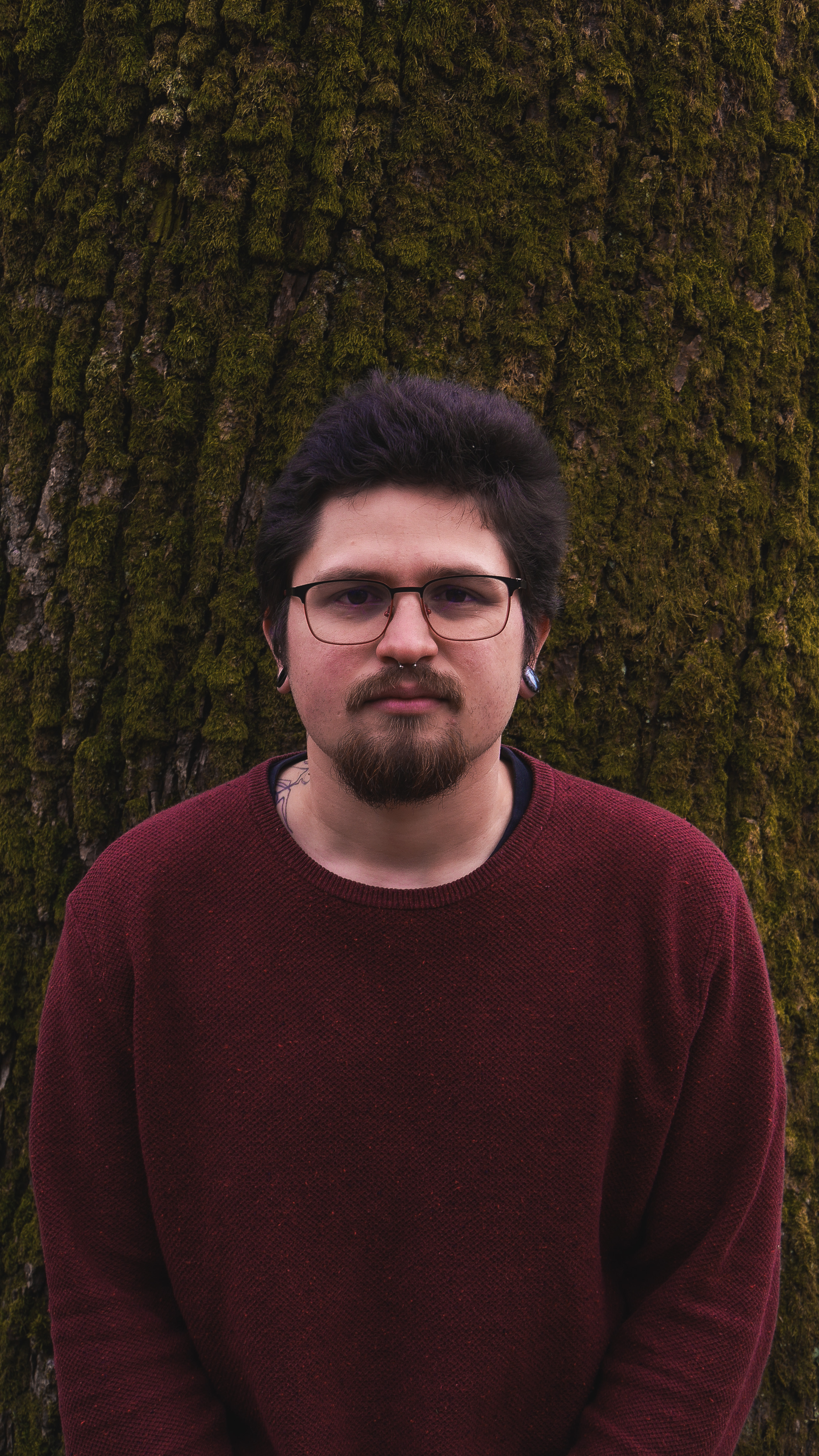 Dylan J. Ras (DRAS) standing in front of a tree